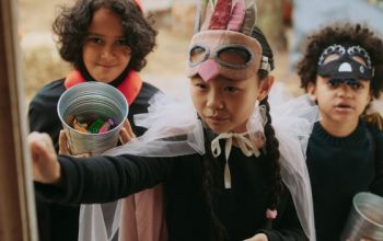 Three young trick or treaters in costume knocking on a door