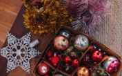 An image of a selection of Christmas decorations, including baubles in a box, a star and some tinsel. 