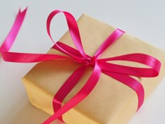 A brown box tied with a pink ribbon in a bow.