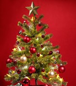 Image of a decorated, green, artificial Christmas tree on a red background.