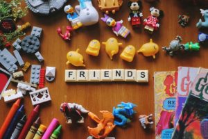 An image of lots of small children's toys surrounding a row of scrabble pieces spelling friends.