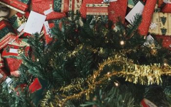 A variety of wrapped Christmas presents under the tree, viewed from above.